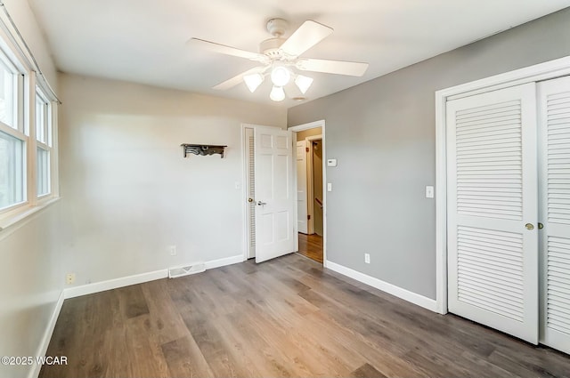 unfurnished bedroom with ceiling fan, visible vents, baseboards, and wood finished floors