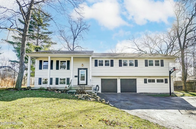split foyer home featuring aphalt driveway, an attached garage, a front yard, and fence