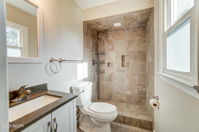 full bath featuring tiled shower, toilet, and vanity