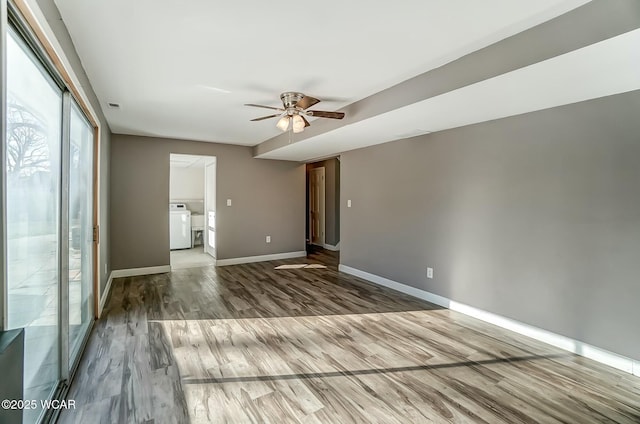 unfurnished room featuring visible vents, washer / clothes dryer, wood finished floors, baseboards, and ceiling fan