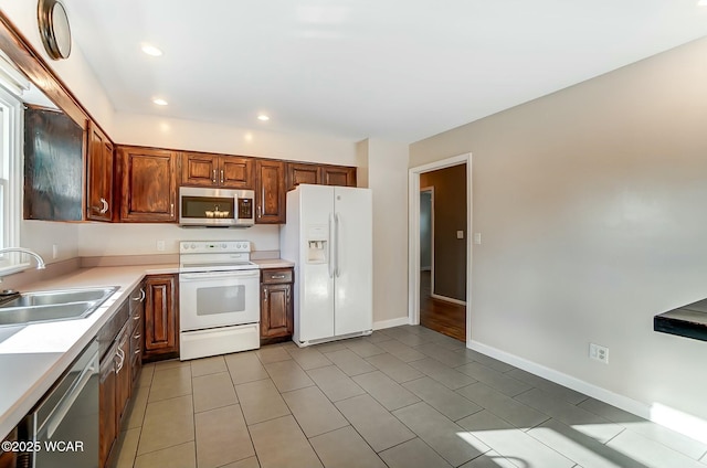 kitchen featuring a sink, recessed lighting, appliances with stainless steel finishes, light countertops, and baseboards