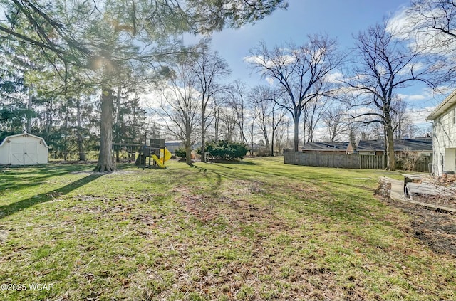 view of yard featuring a storage shed, a playground, fence, and an outdoor structure