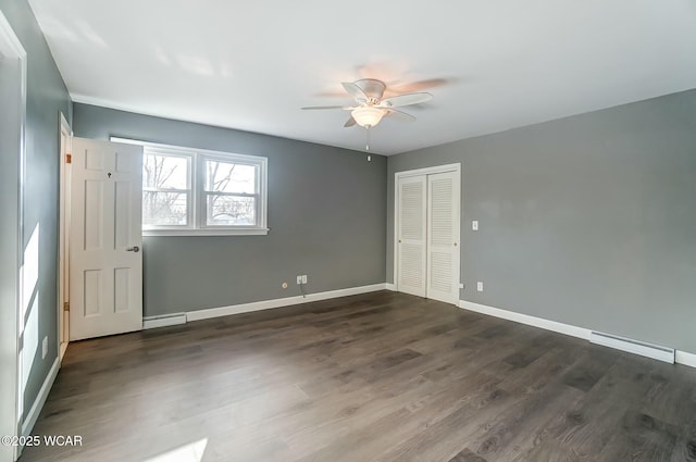 spare room with dark wood-style floors, baseboard heating, baseboards, and ceiling fan
