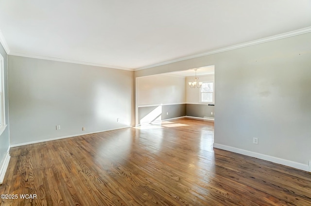 empty room with baseboards, an inviting chandelier, wood finished floors, and crown molding