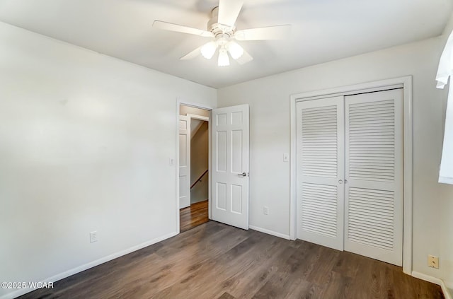 unfurnished bedroom featuring dark wood finished floors, baseboards, a closet, and a ceiling fan