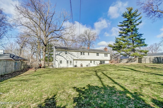 rear view of house with a yard, a fenced backyard, and a chimney
