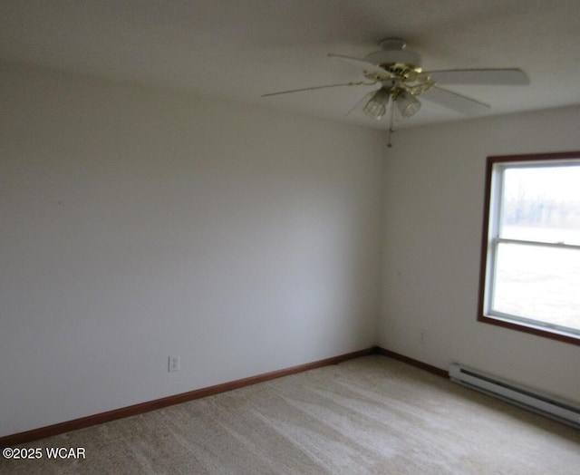 spare room with a baseboard heating unit, light colored carpet, baseboards, and ceiling fan