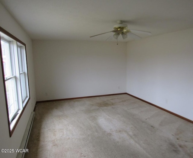 carpeted spare room featuring baseboard heating, ceiling fan, and baseboards