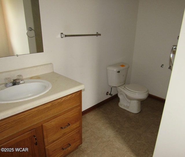 half bath featuring baseboards, toilet, and vanity