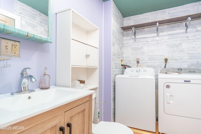 washroom with wooden walls, a sink, washer and dryer, and laundry area