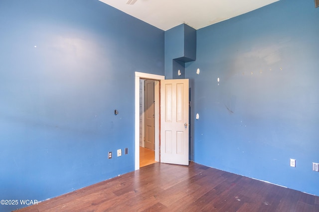 empty room with a high ceiling and wood finished floors
