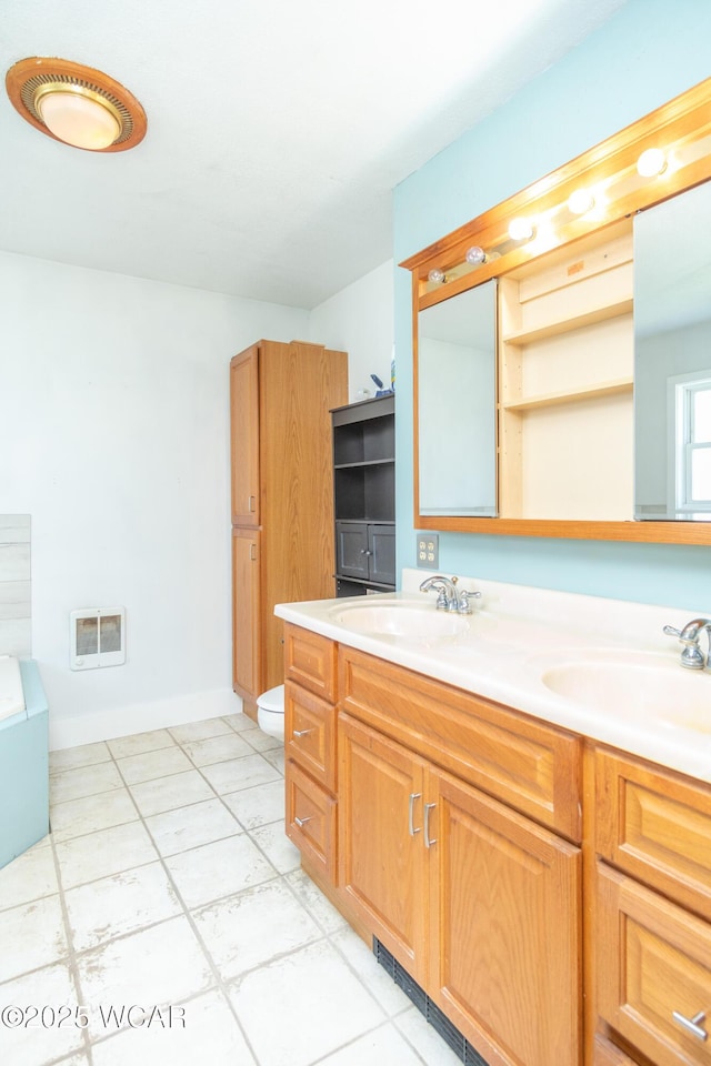 full bathroom featuring toilet, heating unit, a sink, and double vanity