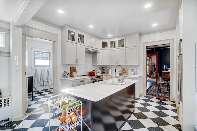 kitchen featuring sink, white cabinetry, a center island with sink, electric range, and radiator heating unit