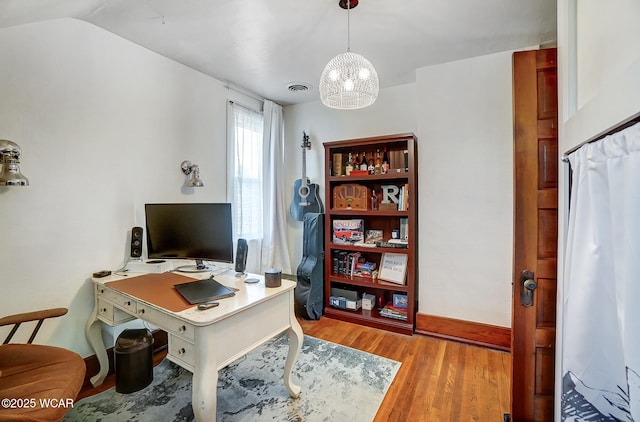 office area with light hardwood / wood-style floors and a notable chandelier