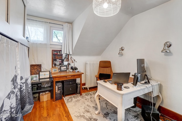 home office with lofted ceiling, radiator heating unit, and light hardwood / wood-style floors