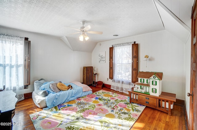 bedroom featuring ceiling fan, wood-type flooring, radiator, and vaulted ceiling