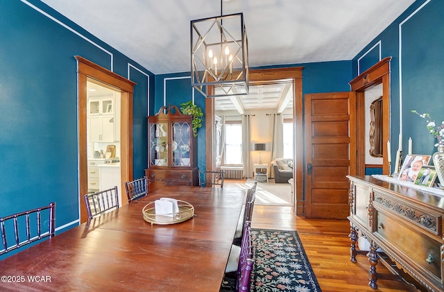 dining space featuring an inviting chandelier, radiator heating unit, and hardwood / wood-style floors