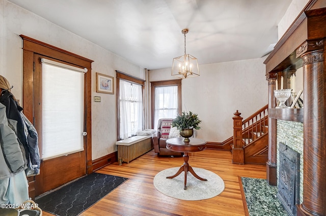 foyer entrance with radiator heating unit, light hardwood / wood-style flooring, and a notable chandelier