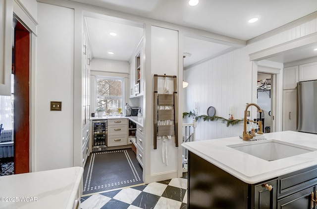 kitchen featuring sink, white cabinets, and beverage cooler