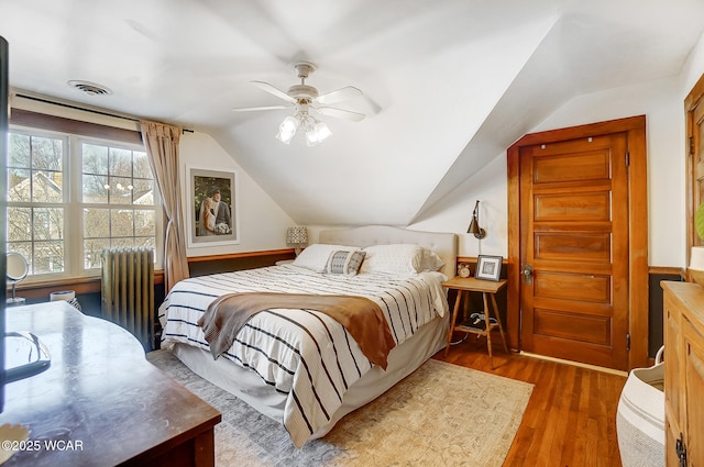 bedroom featuring vaulted ceiling, dark wood-type flooring, radiator heating unit, and ceiling fan