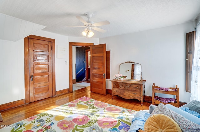 bedroom with ceiling fan, light hardwood / wood-style flooring, and a textured ceiling