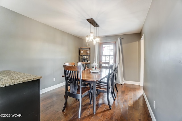 dining space with dark hardwood / wood-style flooring and a chandelier