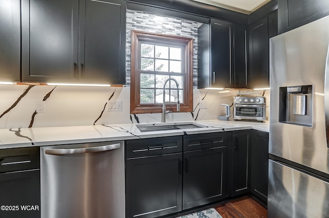 kitchen with light stone counters, sink, dark wood-type flooring, and appliances with stainless steel finishes