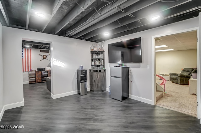 basement featuring dark wood-type flooring and stainless steel refrigerator