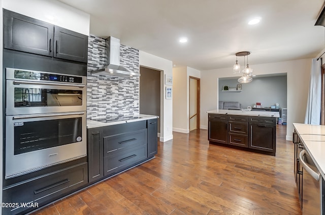 kitchen featuring appliances with stainless steel finishes, dark hardwood / wood-style flooring, decorative backsplash, hanging light fixtures, and wall chimney range hood