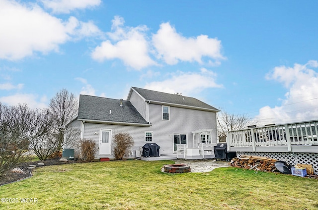 back of property featuring an outdoor fire pit, a deck, and a lawn