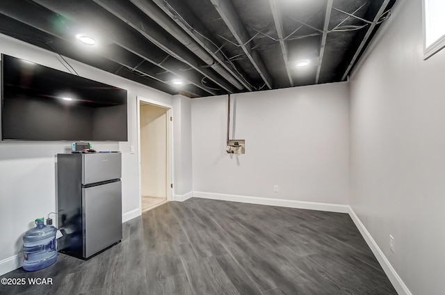 basement featuring hardwood / wood-style floors and stainless steel refrigerator