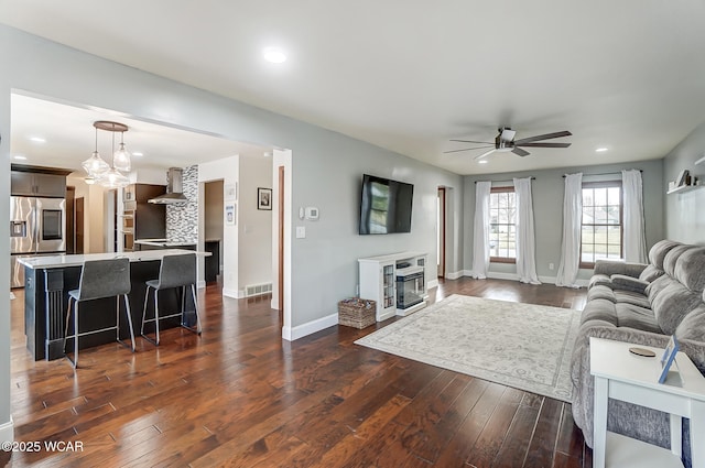 living room with ceiling fan and dark hardwood / wood-style flooring