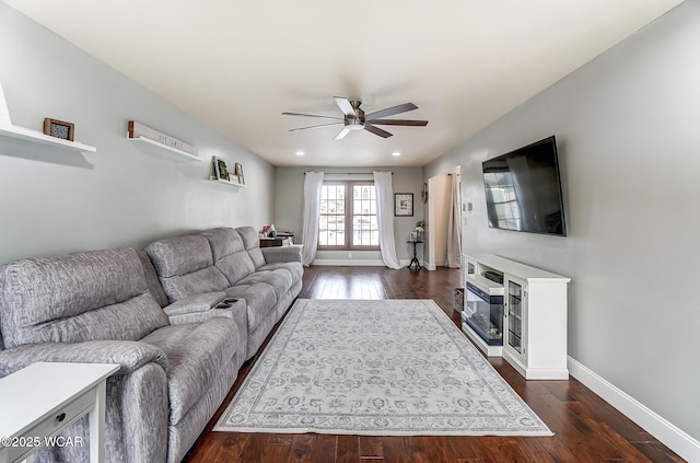 living room featuring dark wood-type flooring and ceiling fan