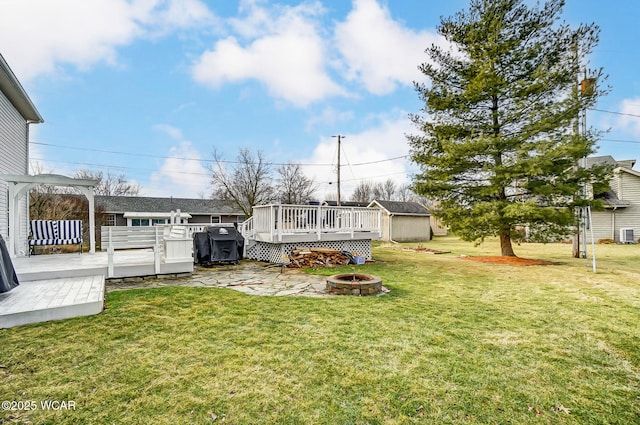 view of yard featuring a wooden deck, a storage unit, central AC, and a fire pit