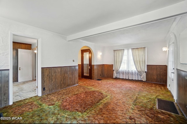 635 Close Ave, Lima, OH 45805 - empty room featuring carpet flooring, arched walkways, wood walls, a wainscoted wall, and visible vents