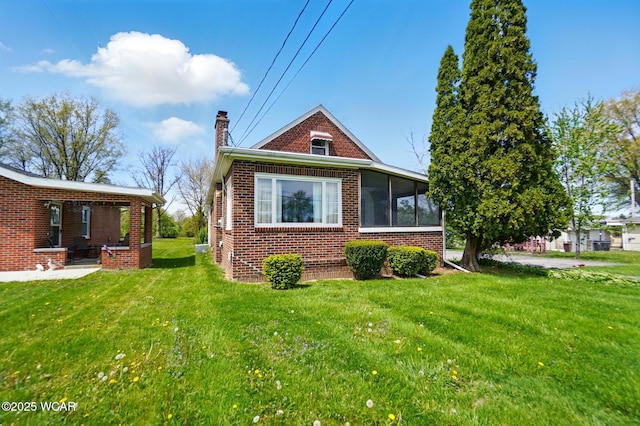 635 Close Ave, Lima, OH 45805 - view of side of home featuring a lawn, brick siding, a chimney, and a sunroom