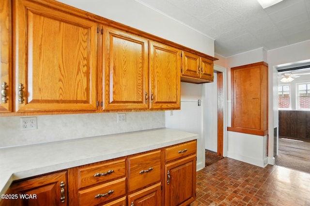 635 Close Ave, Lima, OH 45805 - kitchen featuring brown cabinetry, a ceiling fan, light countertops, baseboards, and brick patterned floor