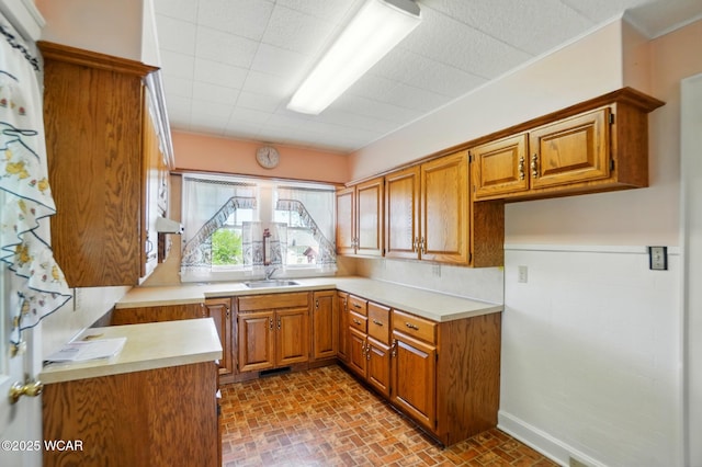 635 Close Ave, Lima, OH 45805 - kitchen featuring light countertops, brick patterned floor, brown cabinets, and a sink