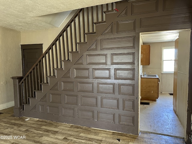 stairs with visible vents, wood finished floors, and baseboards