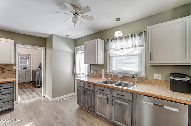 kitchen featuring sink, ceiling fan, light hardwood / wood-style floors, decorative light fixtures, and stainless steel dishwasher