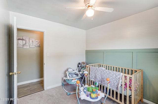 bedroom featuring a crib, ceiling fan, and carpet