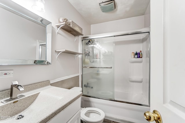 full bathroom featuring enclosed tub / shower combo, vanity, and toilet