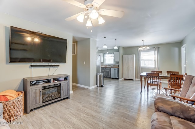 living room with ceiling fan with notable chandelier, sink, and light hardwood / wood-style floors