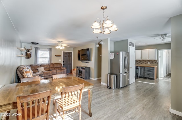 dining space with light hardwood / wood-style floors and ceiling fan with notable chandelier