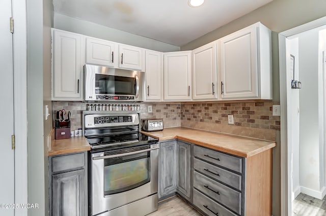 kitchen with stainless steel appliances, white cabinets, and backsplash