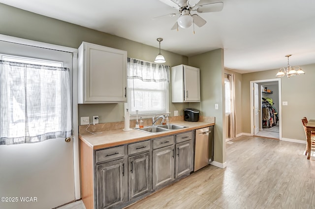 kitchen featuring ceiling fan with notable chandelier, stainless steel dishwasher, sink, and hanging light fixtures