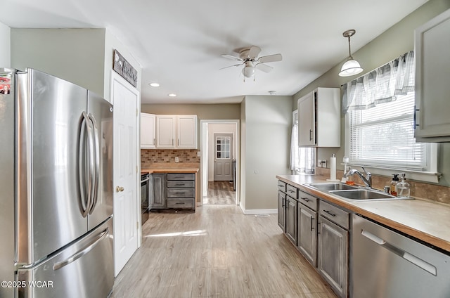 kitchen with sink, ceiling fan, stainless steel appliances, tasteful backsplash, and decorative light fixtures