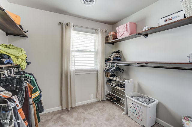 walk in closet with light colored carpet