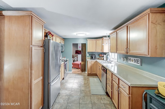 kitchen featuring appliances with stainless steel finishes, sink, light tile patterned flooring, light brown cabinetry, and hanging light fixtures