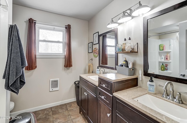 bathroom with heating unit, vanity, toilet, and tile patterned flooring